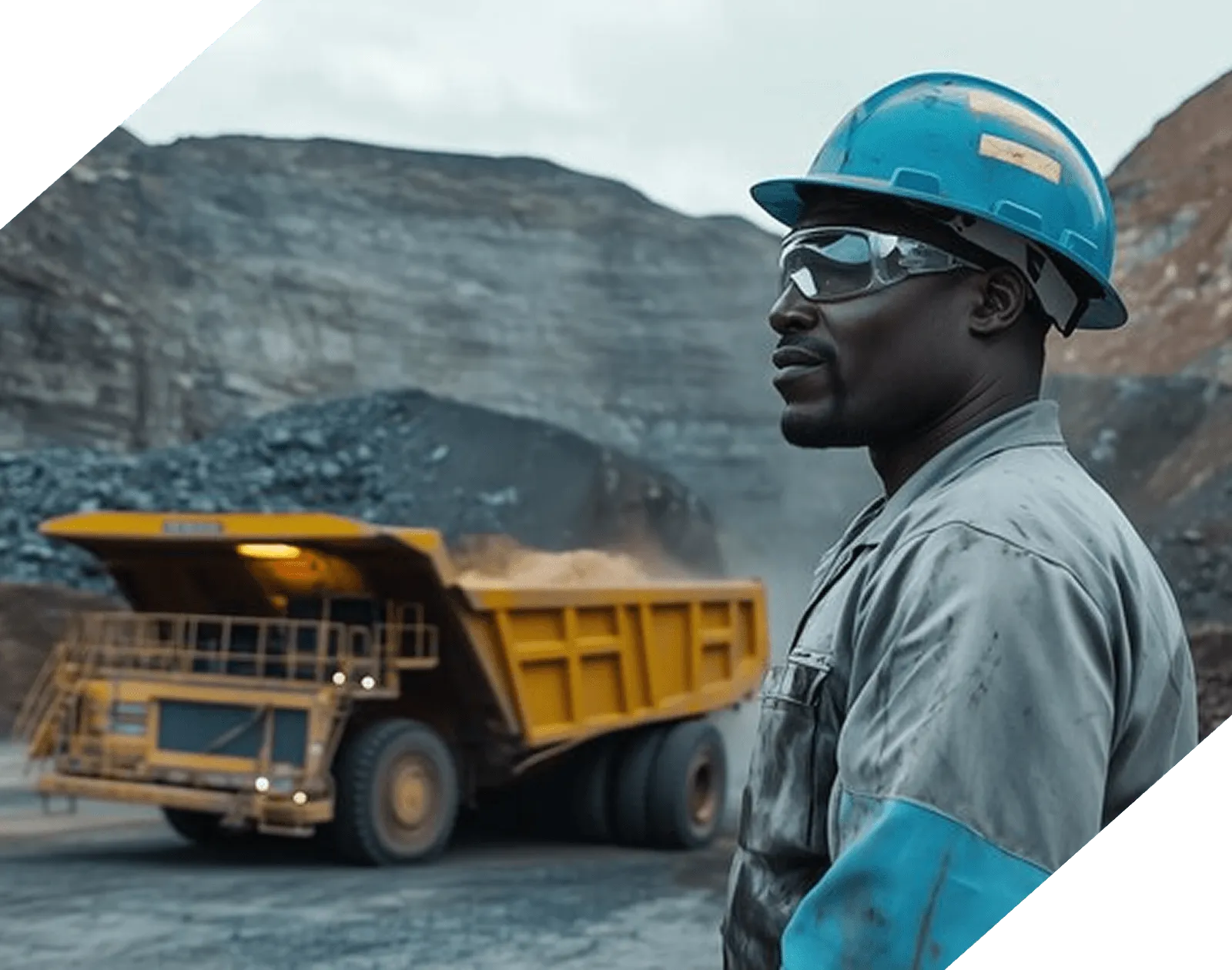a miner looking left with a mining truck in the background
