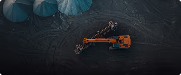 Top-down view of a large orange excavator and other mining equipment on dark ground, possibly at a Bbabsal Mines location.